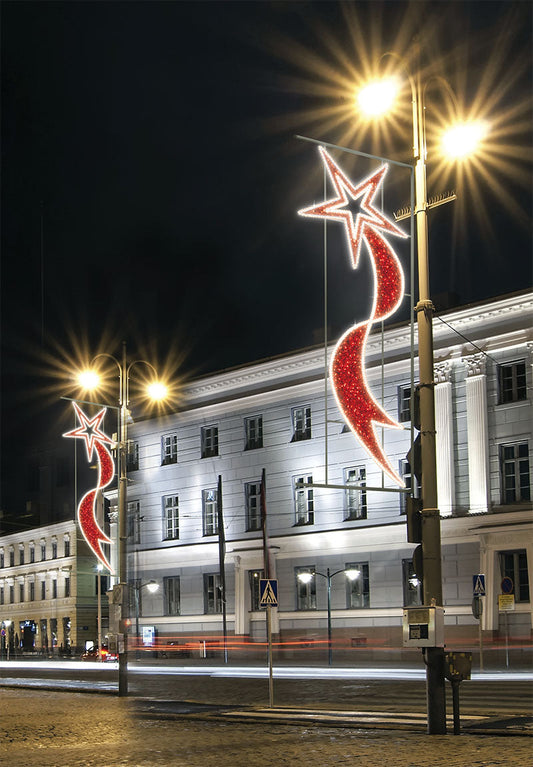Red shooting star LED pole mounts installed on downtown street light poles at night
