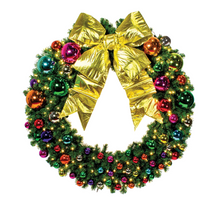A green artificial Christmas wreath decorated with a large shiny gold bow, colorful metallic ornaments in red, green, blue, purple, and orange, and small warm white string lights, isolated on a white background.