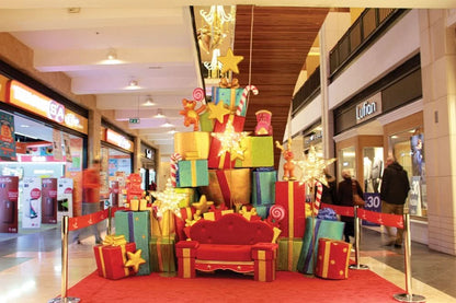 Glitter-covered arch with traditional Christmas toys perched atop brightly colored gift boxes